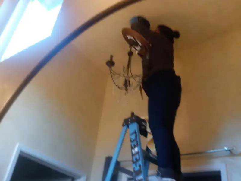 Electrician installing a chandelier in a Centre residence